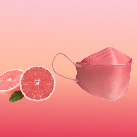 Eine partikelfiltrierende Altruan Designer-Gesichtsmaske (FFP2-Standard) ist elegant neben zwei Grapefruithälften auf einem rosa Hintergrund mit Farbverlauf positioniert und unterstreicht ihr stilvolles Design und ihre ergonomische Passform.