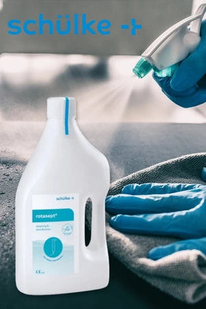 Eine Person mit blauen Handschuhen sprüht ein Desinfektionsmittel auf eine Oberfläche und wischt sie mit einem Tuch ab. Im Vordergrund steht eine weiße Flasche des Produkts „rotasept“ von schülke. Oben im Bild ist das schülke-Logo zu sehen.