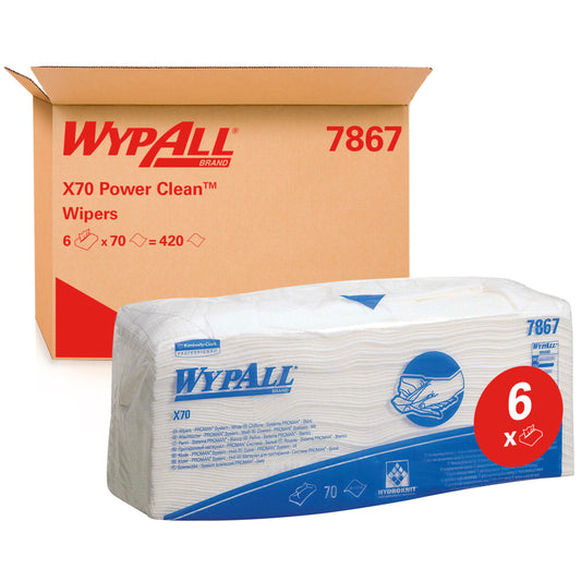 Eine Packung WypAll® X70 Wischtücher - gefaltet / Weiß (6 Beutel x 70 Tücher) der Kimberly-Clark GmbH ist vor einem Karton mit der Aufschrift "WypAll 7867" abgebildet. Das rote "6x"-Etikett hebt die Reinigungstücher in Industriequalität mit blauem Branding hervor.