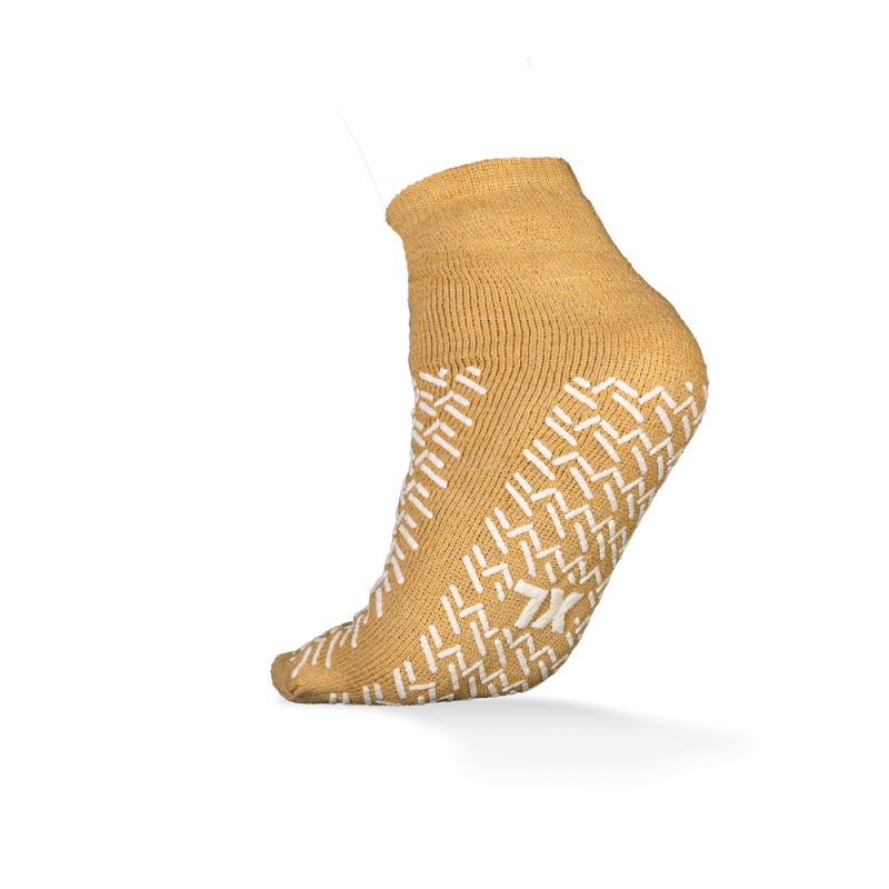 Abgebildet ist ein einzelner senfgelber ECO-PLUS Anti-Rutsch Einwegsocken beidseitig beschichtet von AMPri Handelsgesellschaft mbH auf weißem Hintergrund, mit weißen rutschfesten Griffen und ideal für medizinische Bereiche.