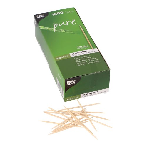 Ένα πράσινο κουτί της PAPSTAR GmbH με την επιγραφή "pure" περιέχει 1.800 στρογγυλές ξύλινες οδοντογλυφίδες (6,8 cm) σε ένα χαρτονένιο δίσκο, μπροστά υπάρχουν διάσπαρτες φιλικές προς το περιβάλλον οδοντογλυφίδες σε μια λευκή επιφάνεια.