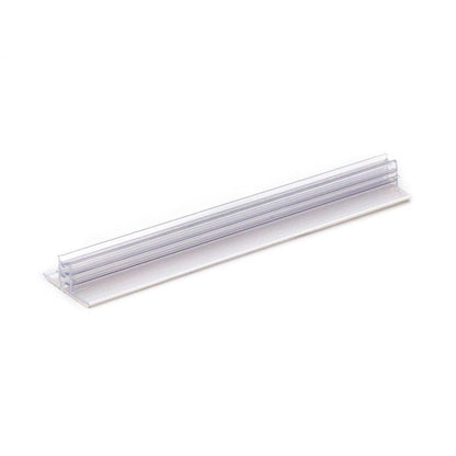 Το Orkla Wound Care AB Clip signieren | Packung (1 Stück) είναι ένας διαφανής πλαστικός κάτοχος ετικετών ραφιού με επίπεδη βάση και κάθετη σχισμή για ετικέτες, κατάλληλος για την οργάνωση ή την επισήμανση αντικειμένων. Απεικονίζεται σε λευκό φόντο.