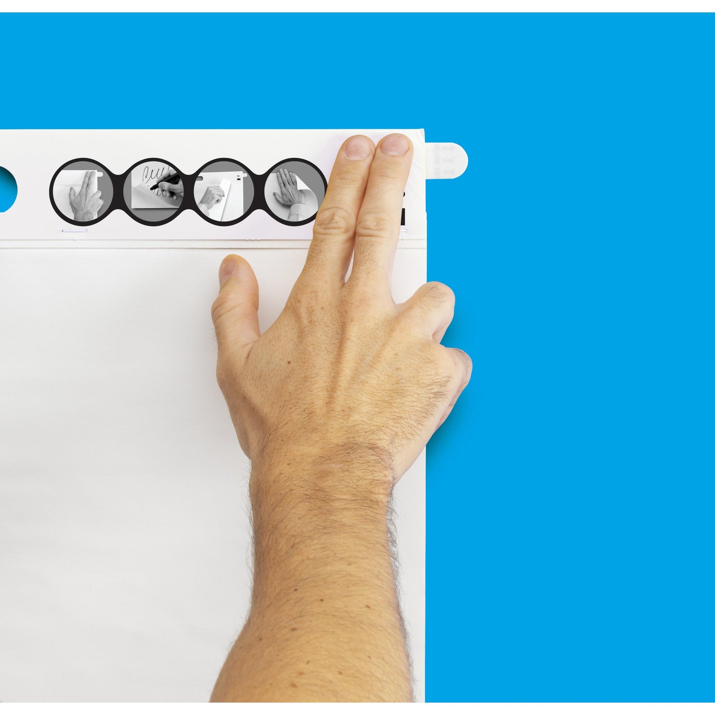 Eine Person befestigt ein Blatt auf einem Flipchart mit blauem Hintergrund unter Verwendung des Post-it® Super Sticky selbsthaftendes Meeting Chart/Flipchart 566 (58,4 x 50,8 cm, 20 Blatt, 2 Blöcke) von 3M Deutschland GmbH mit Command™-Streifen und bebilderter Anleitung.