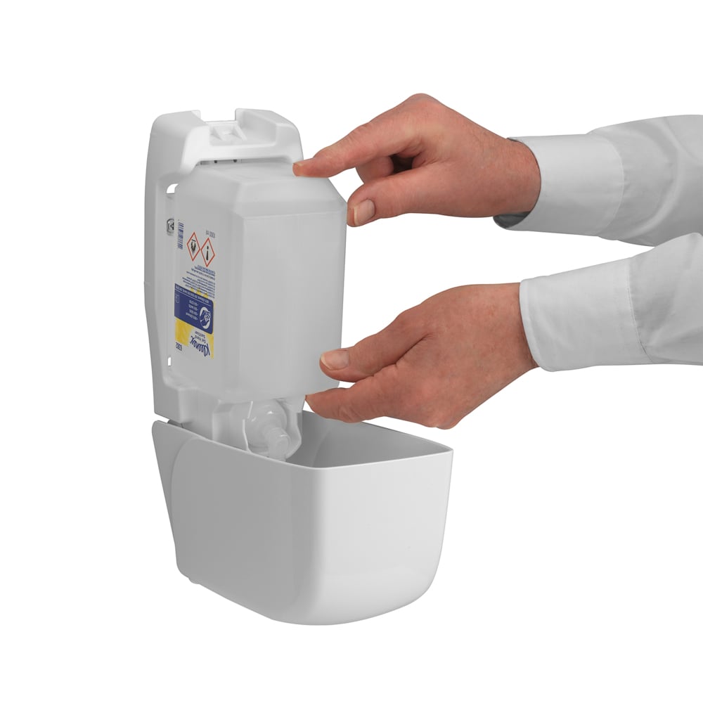 Ένα άτομο γεμίζει έναν επιτοίχιο διανομέα της Kimberly-Clark GmbH Kleenex® Extra Gel Απολυμαντικό Χεριών, τοποθετώντας με τα δύο χέρια μια νέα διαφανή κασέτα 1 λίτρου. Μέσα από το ανοιχτό μπροστινό μέρος είναι ορατά μόνο τα χέρια και οι πήχεις του.