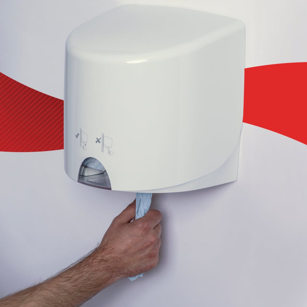 Ένα χέρι τραβάει μια μπλε WypAll® L10 χαρτοπετσέτα για τρόφιμα & υγιεινή από την Kimberly-Clark GmbH από έναν άσπρο τοίχο διανομέα μπροστά από έναν άσπρο τοίχο με κόκκινη κυματιστή γραμμή.