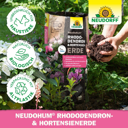Ένα άτομο με πλούσιο NeudoHum Rhododendron & Hortensien Erde από το Neudorff Shop, ιδανικό για την προώθηση της υγιούς ανάπτυξης των ροδόδεντρων.