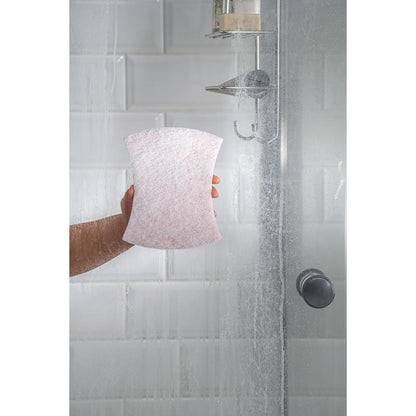 Ένα χέρι χρησιμοποιεί τον Scotch-Brite® Bath Griffschwamm XXL από την 3M Deutschland GmbH σε μια γυάλινη ντουζιέρα με λευκά πλακάκια Subway και μεταλλικό ντους, καθώς οι λεκέδες νερού στην πόρτα υπογραμμίζουν την ανάγκη για αποτελεσματικό καθαρισμό του μπάνιου.