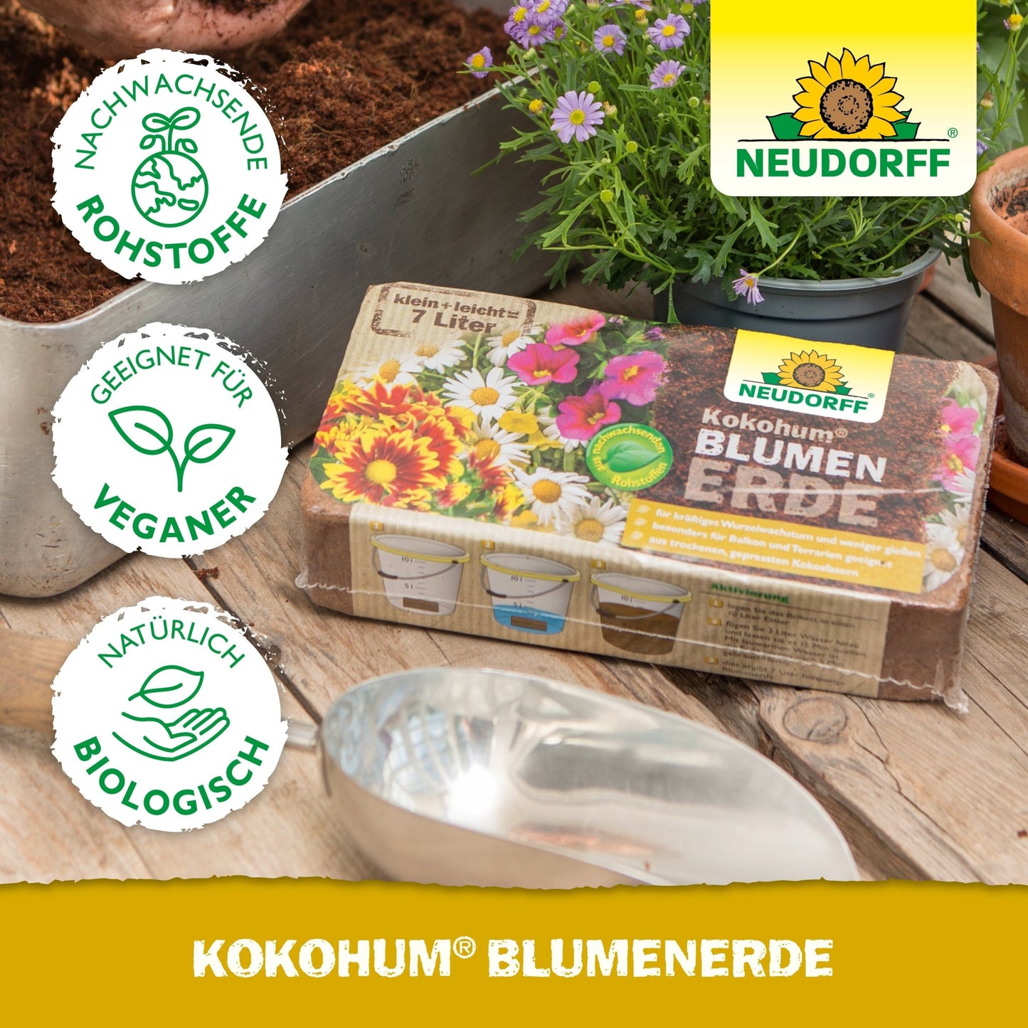 Μια συσκευασία Neudorff Shop Kokohum BlumenErde βρίσκεται πάνω σε ένα τραπέζι με χώμα, μια μεταλλική σπάτουλα, γλάστρες και φυτά. Τα σύμβολα δείχνουν ότι το προϊόν είναι βίγκαν, βιολογικό και κατασκευασμένο από ανανεώσιμα υλικά.