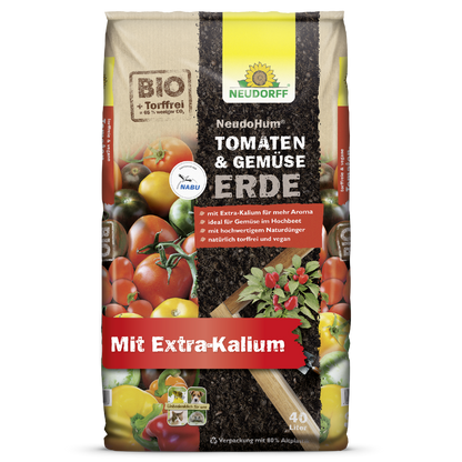 Μια σακούλα 40L Neudorff Shop NeudoHum Tomaten- & GemüseeErde, χωρίς τύρφη και βίγκαν με επιπλέον κάλιο, ιδανική για καλοκαιρινά λαχανικά. Βιολογική συσκευασία με ντομάτες, διάφορα λαχανικά, χώμα και φύλλα φυτών.