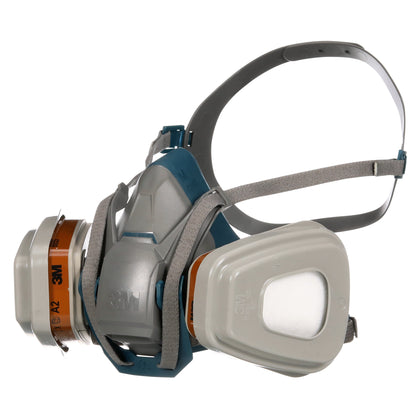 Die 3M™ Quick Latch-Atemschutzmaske 6502QLKIT-1 von 3M Deutschland GmbH mit austauschbaren A2P3-Filtern (1x6502, 2x6055, 2x5935, 2x501) zeigt verstellbare graue Bänder und ein grau-blaues Maskengehäuse mit sichtbarem Logo.