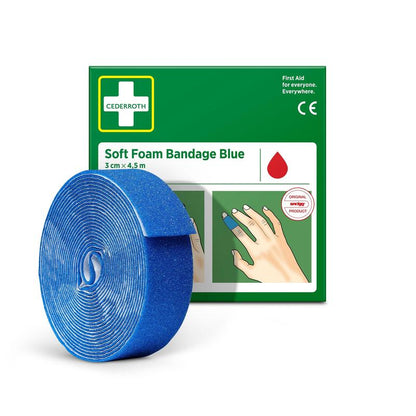 Ένα ρολό Cederroth Soft Foam Binde μπλε 3x450cm από την Orkla Wound Care AB απεικονίζεται μπροστά από τη πράσινο-λευκή συσκευασία, στην οποία ο μπλε επίδεσμος είναι τυλιγμένος γύρω από ένα δάχτυλο.