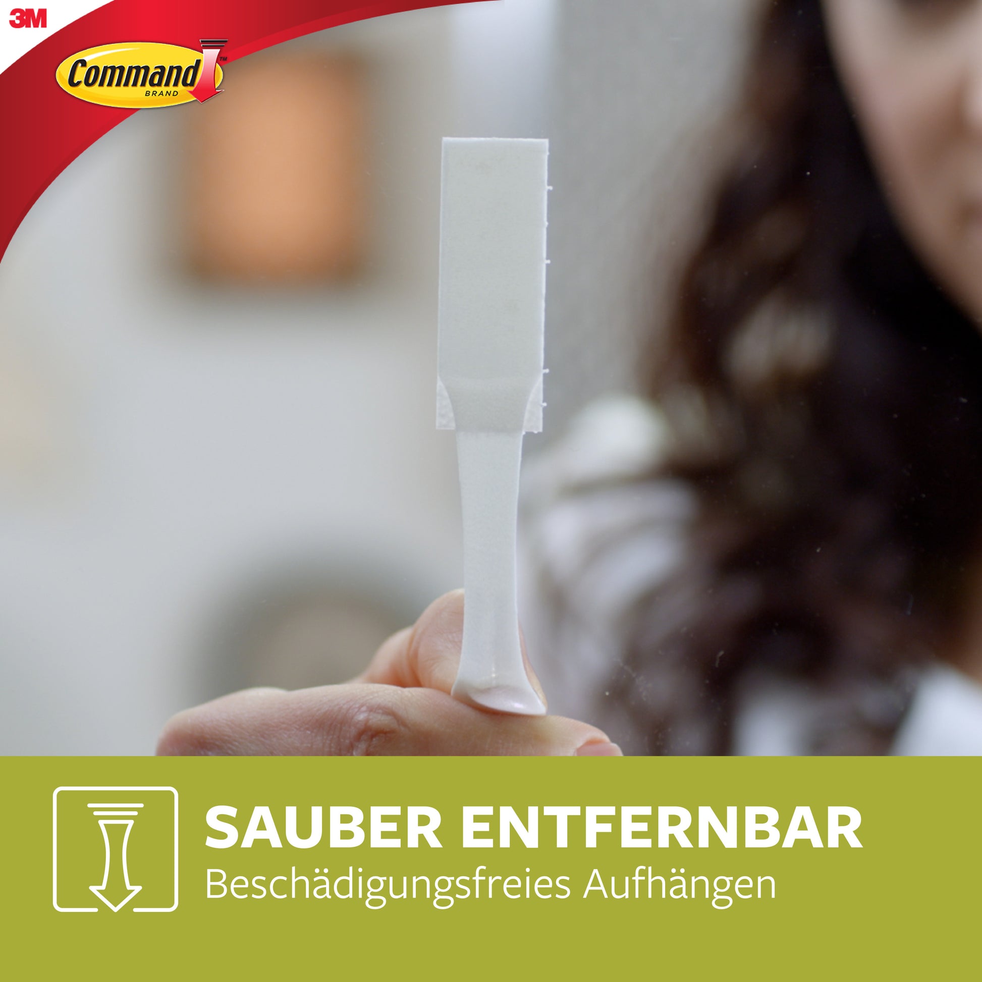 Eine Hand hält einen weißen Streifen im Vordergrund. Oben links ist das 3M Command™-Logo zu sehen, darunter der deutsche Text "Sauber entfernbar - Beschädigungsfreies Aufhängen". Produkt: Kleine und mittelgroße Bilder-Montage-Streifen, Vorteilspack, 17203.