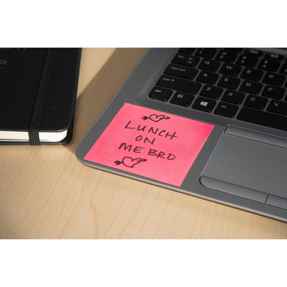 Ένας κύβος σημειώσεων Post-it® (76x76mm, 450 φύλλα, 100% PEFC) της 3M Deutschland GmbH σε ροζ χρώμα βρίσκεται πάνω σε πληκτρολόγιο φορητού υπολογιστή με το μήνυμα "LUNCH ON ME BRO" και σχέδια καρδιών. Ένα κλειστό μαύρο σημειωματάριο βρίσκεται δίπλα σε ένα ανοιχτόχρωμο ξύλινο τραπέζι.