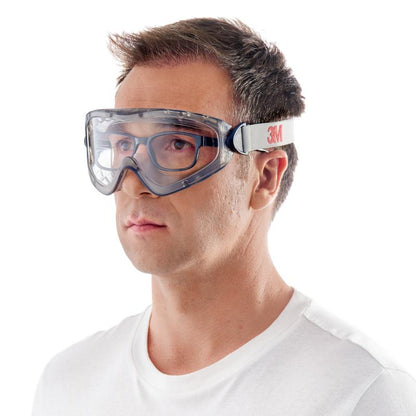 Ένας άντρας με κοντά καστανά μαλλιά και ένα απλό λευκό T-Shirt φορά μπροστά από ένα λευκό φόντο τα γυαλιά προστασίας 3M™ 2890, σφραγισμένα, διαφανής φακός της 3M Deutschland GmbH με μια λευκή ελαστική ταινία με την επιγραφή "3M".