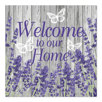 Πινακίδα με μοβ κείμενο "Welcome to our Home" σε γκρι ξύλινο φόντο, διακοσμημένη με λουλούδια λεβάντας και τρεις λευκές πεταλούδες, αναφερόμενη στα PAPSTAR 20 χαρτοπετσέτες, 33x33cm, 3-στρώσεων από την PAPSTAR GmbH.