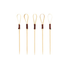 Σαράντα PAPSTAR Fingerfood Picker 10 cm "Loop" Cocktail Picks της PAPSTAR GmbH, ιδανικά για σνακ και fingerfood, χαρακτηρίζονται από μοναδικό σχεδιασμό Loop με τμήματα τυλιγμένα σε σκούρο καφέ, τα οποία είναι τοποθετημένα όρθια μπροστά από ένα απλό λευκό φόντο.