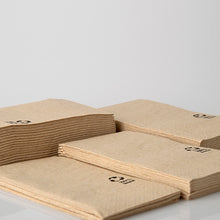 Τέσσερις στοίβες χαρτοπετσέτες PAPSTAR, 3 στρώσεων, 33x33 εκ., φυσικό χρώμα, από ανακυκλωμένο χαρτί (100 τεμάχια) της PAPSTAR GmbH βρίσκονται σε μια λευκή επιφάνεια. Κάθε ανακυκλωμένη χαρτοπετσέτα είναι εξοπλισμένη με ένα μικρό μαύρο σύμβολο ανακύκλωσης στη γωνία.