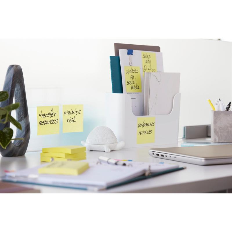 Ένα σύγχρονο γραφείο με ένα μπλοκ 3M Post-it® Super Sticky Notes (76 mm x 76 mm, 90 φύλλα, 100% PEFC) σε έναν γυάλινο διαχωριστικό, μια φιγούρα χελώνας, φακέλους σε μια θήκη εγγράφων, ένα κλειστό φορητό υπολογιστή, στυλό και ένα σημειωματάριο.