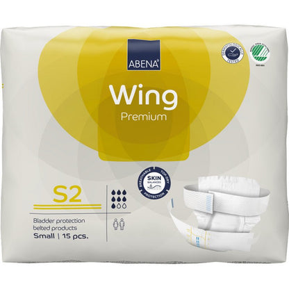 Μια συσκευασία ABENA Wing Premium από την Abena Re-Seller GmbH περιέχει 15 μικρά προϊόντα ακράτειας με ζώνη για προστασία και άνεση. Στη κυρίως λευκή και κίτρινη συσκευασία απεικονίζονται πληροφορίες προϊόντος και μια εικόνα πάνας.