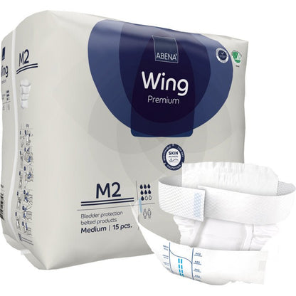 Παρουσιάζεται ένα πακέτο της Abena Re-Seller GmbH ABENA Wing Premium που περιέχει 15 μεσαίου μεγέθους προϊόντα ακράτειας με ζώνη. Μπροστά απεικονίζεται ένα προϊόν που τονίζει την απόλυτη προστασία για ενήλικες.