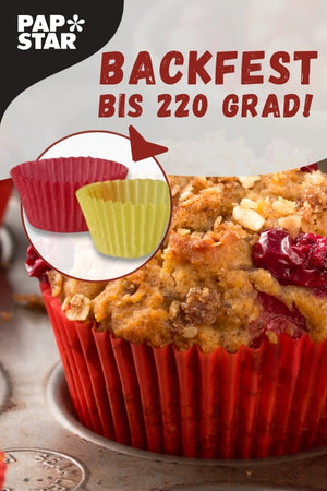 Ein Muffin in einer roten Papierbackform, umgeben von weiteren Backutensilien. Es gibt zwei kleine Backformen, eine in Rot und eine in Grün, die nebeneinander abgebildet sind. Darüber steht der Text 'PAP*STAR BACKFEST BIS 220 GRAD'.