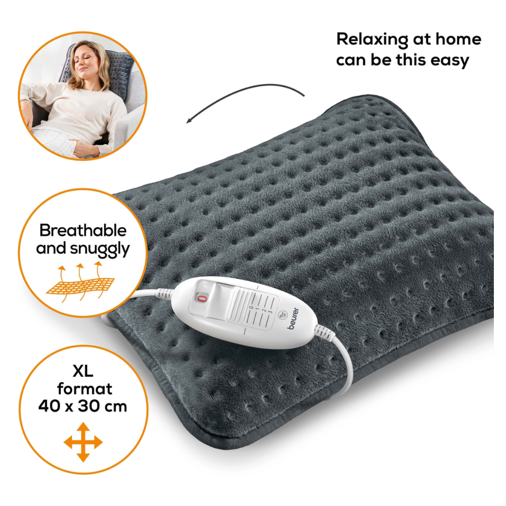 Μια γυναίκα ξαπλώνει σε έναν καναπέ και χαμογελά με κλειστά μάτια. Δίπλα της βρίσκεται ένα Beurer HK 48 Μαξιλάρι Θέρμανσης Καναπέ Cosy σε σκούρο γκρι με λευκή μονάδα ελέγχου. Στο μαξιλάρι αναγράφεται «Τόσο εύκολο μπορεί να είναι να χαλαρώσετε στο σπίτι», «Αναπνεύσιμο και άνετο» και «XL-Διαστάσεις 40 x 30 cm».