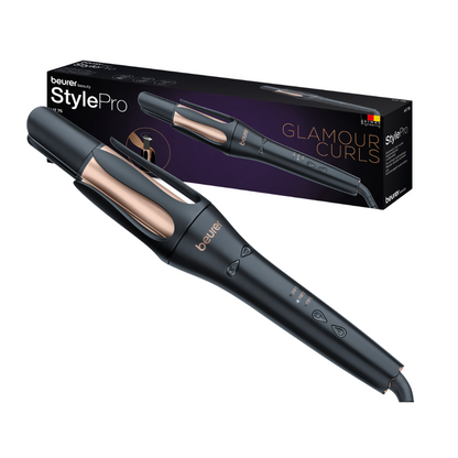 Ένα Beurer HT 75 Αυτόματο Σίδερο για Μπούκλες από την Beurer GmbH σε κομψό σχέδιο σε μαύρο και ροζ χρυσό φαίνεται μαζί με το κουτί συσκευασίας του με την επιγραφή «Glamour Curls». Το αυτόματο σίδερο για μπούκλες διαθέτει ψηφιακά χειριστήρια στη λαβή και τετραπλή έξοδο ιόντων. Το κουτί δείχνει μια εικόνα του σίδερο και τη μάρκα.