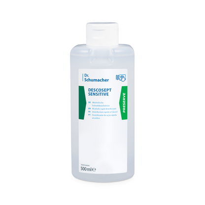 Ένα μπουκάλι 500 ml Dr. Schumacher Descosept Sensitive Schnelldesinfektion της Dr. Schumacher GmbH, σχεδιασμένο για την απολύμανση ιατρικών προϊόντων. Το διαφανές μπουκάλι διαθέτει μια λευκή ετικέτα με το όνομα του προϊόντος και οδηγίες χρήσης σε πολλές γλώσσες, συμπεριλαμβανομένων των Αγγλικών, Γερμανικών και Γαλλικών, καθώς και μια πράσινη ετικέτα «Preserve» στο πλάι.