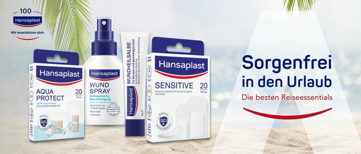 Werbebanner von Hansaplast mit dem Slogan ‚Sorgenfrei in den Urlaub – Die besten Reiseessentials‘. Zu sehen sind vier Hansaplast-Produkte im Vordergrund auf Sand vor tropischem Hintergrund mit Palmen: AQUA PROTECT Pflaster (20 Stück, wasserdicht), WUNDSPRAY (antiseptische Wundreinigung), WUNDHEILSALBE (zur Heilung geschädigter Haut) und SENSITIVE Pflaster (20 Stück, hautverträglich). Links oben das Hansaplast-Logo mit dem Hinweis ‚Seit 100 Jahren – Wir beschützen dich‘.