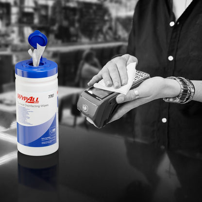 Κάποιος χρησιμοποιεί ένα μαντηλάκι απολύμανσης επιφανειών WypAll® (Kimberly-Clark GmbH) από μια ανοιχτή λεκάνη διανομής για την απολύμανση ενός τερματικού καρτών. Ο λευκός κουβάς διανομής (200 μαντηλάκια) βρίσκεται στον πάγκο, το φόντο είναι θολό.