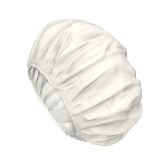 Eine weiße TENA ProSkin Shampoo Cap Waschhaube mit Gummiband. Die Haube ist aus glattem, wasserdichtem Material und ist für praktische und komfortable Haarwäsche konzipiert, wobei sie das Haar vor Nässe schützt. Diese TENA Einweg-Waschhaube ist vor einem schlichten weißen Hintergrund abgebildet.