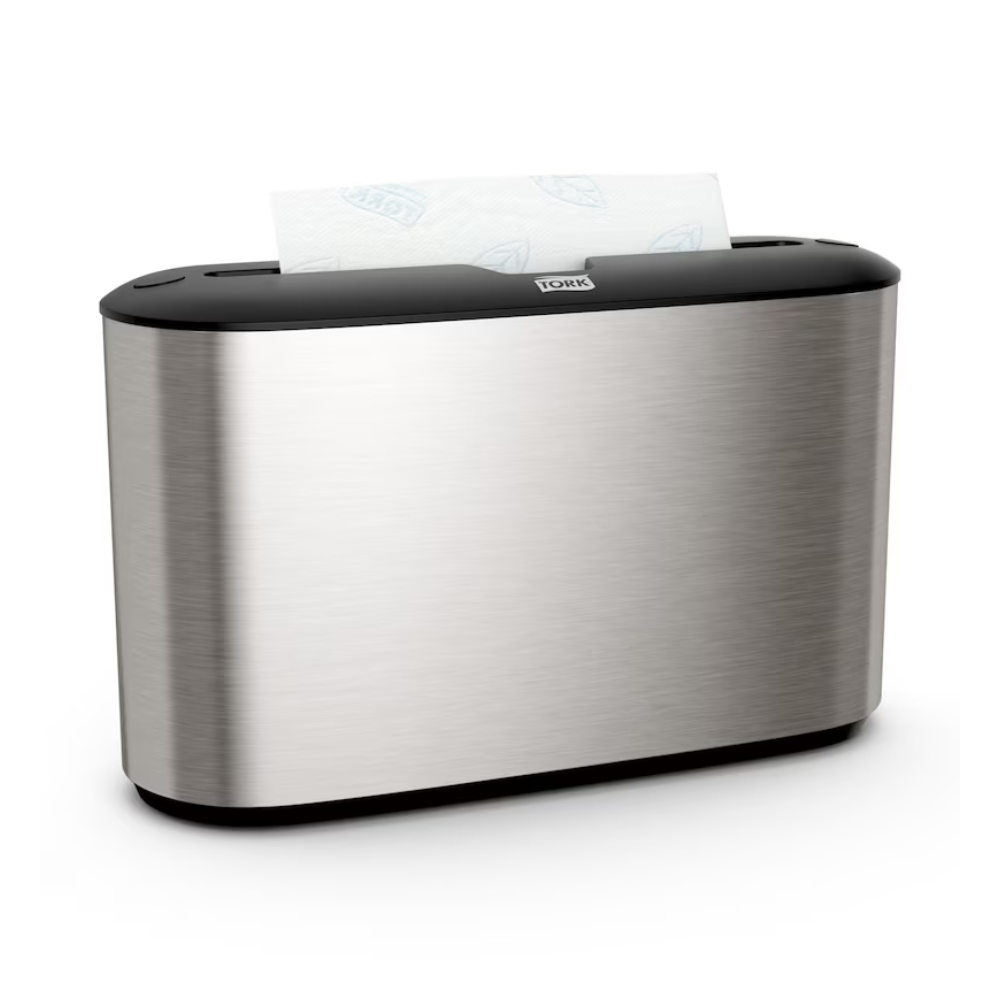 Ο Tork Xpress® 460005 επιτραπέζιος διανομέας για πετσέτες πολλαπλών διπλώσεων από την Essity Professional Hygiene Germany GmbH ξεχωρίζει για τον απαιτητικό σχεδιασμό από ανοξείδωτο ατσάλι. Η ασημένια μεταλλική εξωτερική του όψη τονίζεται από μια μαύρη κορυφή, ενώ ένα τμήμα λευκών χάρτινων πετσετών προεξέχει κομψά από την επάνω σχισμή. Ιδανικό για χρήστες πετσετών πολλαπλών διπλώσεων που εκτιμούν τόσο το στυλ όσο και τη λειτουργικότητα.