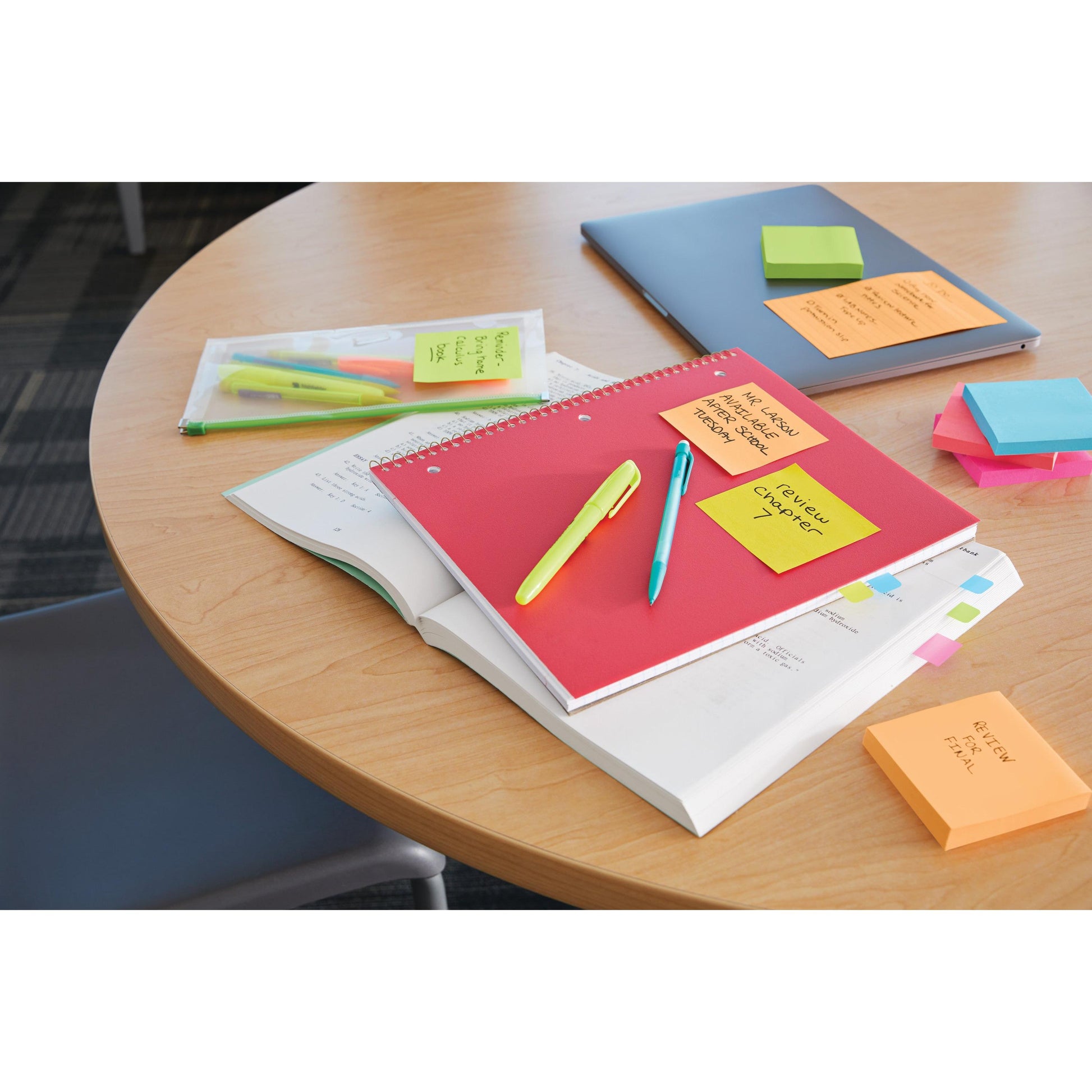 Ein runder Holztisch mit einem geschlossenen Laptop, Notizbüchern, Stiften in einer Plastiktasche, Textmarkern, Erinnerungsnotizen und einem Stapel 3M Deutschland GmbH Post-it® Super Sticky Notes Würfel, Gelb (76 mm x 76 mm). Ein Stuhl ist teilweise sichtbar.