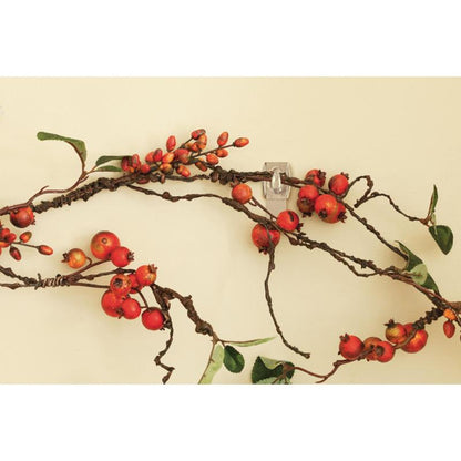 Ένα διακοσμητικό κλαδί με κόκκινα μούρα και πράσινα φύλλα κρέμεται σε μπεζ τοίχο, υποστηριζόμενο από το Command™ Mini-Haken, transparent, mit transparenten Strips, 17006CLRFGN von 3M Deutschland GmbH - τέλεια αποθήκευση χωρίς τρύπημα.