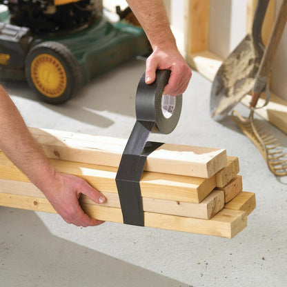 Σε ένα εργαστήριο, κάποιος ασφαλίζει ξύλινα σανίδια με Scotch® Extremium™ Ultra Υψηλής Απόδοσης Κολλητική Ταινία DT17 (10 μ x 24 mm) της 3M Deutschland GmbH. Κοντά βρίσκονται ένα φτυάρι, μια τσουγκράνα και μια χλοοκοπτική μηχανή.