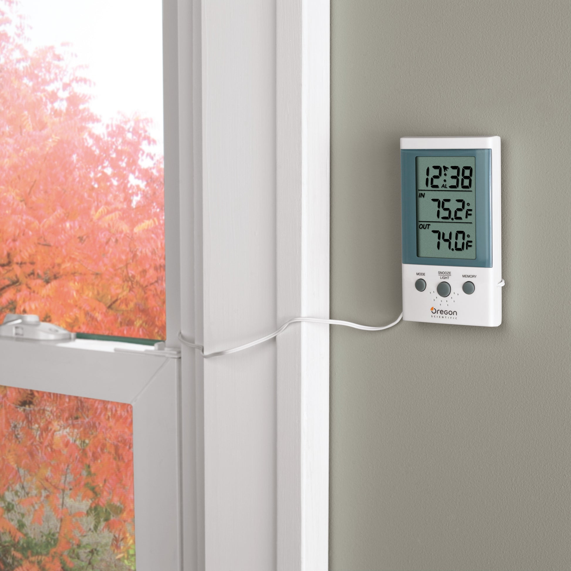 An einem Fenster mit 3M Scotch-FIX™ doppelseitigen Innenmontagequadraten (25 mm x 25 mm, 16 Stück) befestigt, zeigt das Thermometer 12:38, Innentemperatur 75,2°F, Außentemperatur 74,0°F; draußen ist Herbstlaub zu sehen.