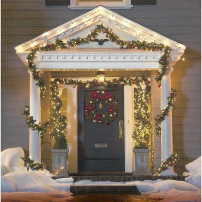 Ein gemütlicher Weihnachtseingang erstrahlt mit Lichterketten, die mit Command™ Outdoor Lichter-Clips, 17017CLR-AWPU (8 Clips + 10 Streifen) von 3M Deutschland GmbH aufgehängt wurden, Schnee auf den Stufen und Girlanden, die die dunkle Tür einrahmen, für eine charmante Außenbeleuchtung Befestigung.